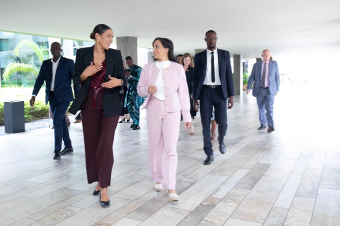 Two people walk, in discussion. More people walk behind the pair.