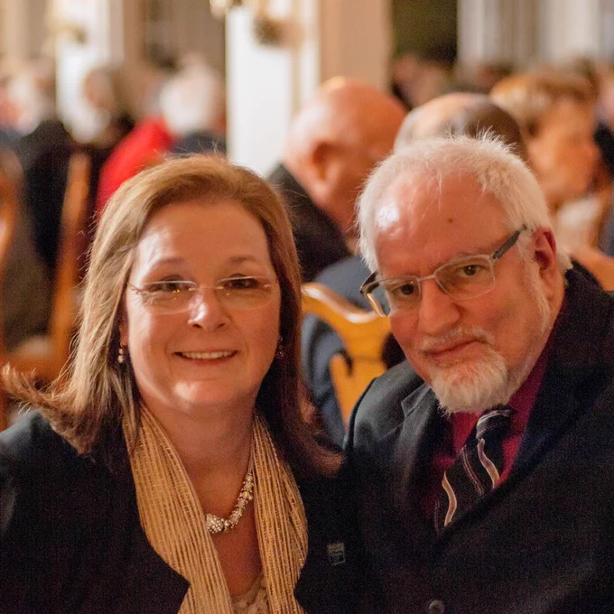 Martha and Doug smile together while sitting at their table at a celebration.