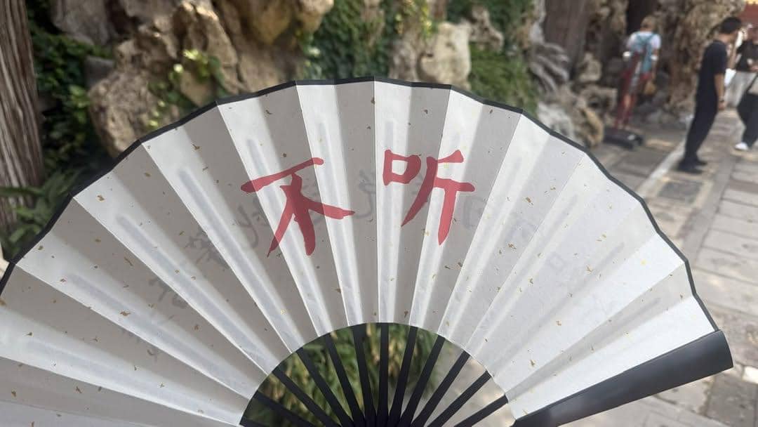 wangjupaian's tweet photo. 【故宫买题字折扇，天安门安检叮嘱别打开】近日有网友分享了一段颇为荒诞的经历：清晨在故宫买了一把折扇，随后前往天安门附近，没想到这把纪念品在安检时引起了注意。

扇子正面文字：“你如何向朕说起此等话来。”
扇子反面文字：“不听”

安检人员反复查看扇面文字，还专门向上级汇报。上级看完后，认为文字“有嘲讽意味”，最后虽然放行，却叮嘱网友：“千万别拿出来，别打开。”

网友后来才发现，自己所在的位置其实是北京市劳动人民文化宫。想起二十多年前天安门广场可以自由进出，再看看如今一把折扇都要层层请示，只剩下一句感叹：“防民如寇。”