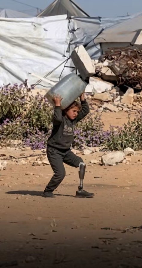 Abdullah_Om3r03's tweet photo. A heartbreaking scene that captures the depth of suffering in Gaza… 💔

A little girl lost her foot to the war, but she could not lose her will. She walks with a prosthetic limb, carrying a container of water to provide for her family, in a silence that breaks the heart.

She has conquered pain with patience and, through her unwavering strength, painted a picture that words can hardly describe… a picture of hope growing in the midst of pain. 💔🥺