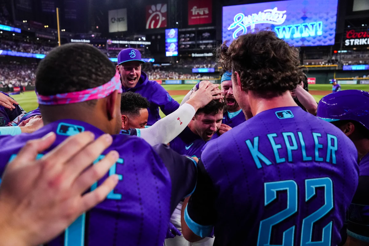The D-backs celebrate after walking it off. They are all wearing purple Serpientes City Connect uniforms. 