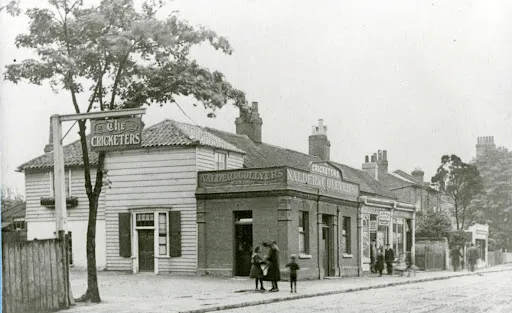 SaveUKPubs's tweet photo. The Cricketers stood on Sutton Green long before Sutton became the busy town people know today. Back in the early 1800s, when the village still revolved around the green and its pond, this little beer house was already serving locals after a day's work. Across the road, cricket matches were played on the green years before Sutton Cricket Club was even officially formed in 1857.

By the 1850s, coachman William Featherstone was running the pub. Families lived there, grandchildren grew up in its rooms, and lodgers came and went. Like so many old British pubs, it wasn't just somewhere to grab a pint. It was part of everyday life.

Ownership changed hands over the decades. There were inheritance disputes, brewery sales, even a High Court case in the 1880s before the building was auctioned. Yet the pub carried on. Joseph Watson, a former railwayman, became landlord around 1880, and after his death his wife Eliza kept the place going for another twenty years. When she passed away, their daughter Rose and her husband took over, followed by the next generation. Three generations of one family ended up behind the same bar.

For more than 150 years, The Cricketers watched Sutton grow around it. Horses gave way to motor cars. Quiet country roads became busy streets. But the old building remained, one of the last reminders of what Sutton once looked like.

Historic England once described it as one of the few surviving buildings that reflected Sutton's early history and character.

Then, in 2016, it was removed from the listed register.

Not long afterwards, it was demolished.

Another old pub gone. Another piece of Britain's story that won't be coming back.