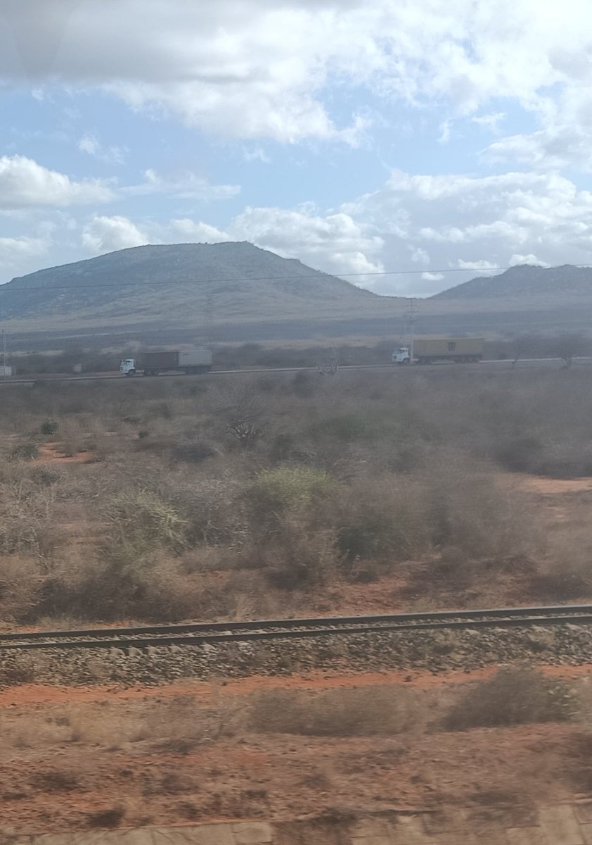 gathara's tweet photo. A very Kenyan sight: images, from the SGR train running on the hideously expensive track, of the existing metre gauge track it was constructed next to, and the trucks it was supposed to get off Mombasa road - which is now to be expanded to accommodate more of those very trucks. https://t.co/v0hSVcOS1c