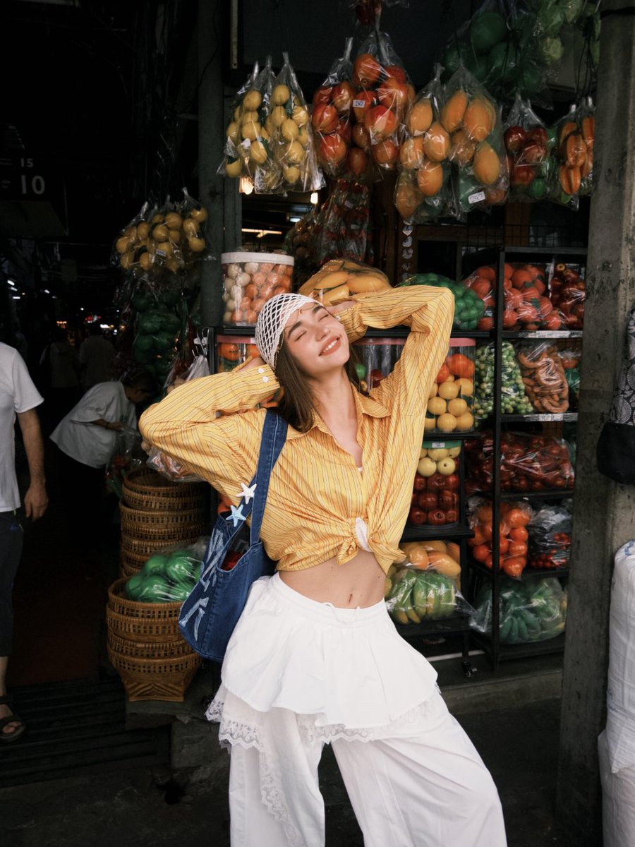LunarTally's tweet photo. Ducked into a busy fruit market, colors everywhere and vendors calling out. Warm yellow striped shirt tied loosely, lace-trimmed white wide-leg pants, canvas bag on. Snapped a few shots next to fresh fruit piles, market energy and undone styling blending perfectly 🧡🍊 https://t.co/olEGwA7m3u