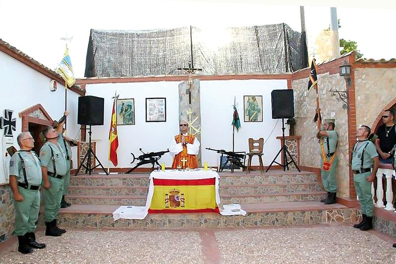 outsidersesp's tweet photo. Historia de un nazi alemán y su fortín de Alicante.

El exlegionario alemán Joachim Fiebelkorn, uno de los neonazis más temidos de la segunda mitad del siglo XX, investigado por una masacre en Italia y odiado en Bolivia por su papel como colaborador de la dictadura junto al capitán de la Gestapo Klaus Barbie, tiene un fortín en Alicante donde es arropado por guardias civiles, militares y camaradas legionarios.

En la localidad alicantina de Rojales hay una finca que emula a un castillo fortificado, con sus torretas, almenas, innumerables cámaras de seguridad y dos águilas imperiales custodiando un portón sobre el que se clava una gran bandera de España. En su interior hay un patio en el que un sacerdote celebra misa flanqueado por dos ametralladoras de gran calibre, un Cristo y una imponente Cruz de Hierro alemana. Se trata de un oficio veraniego por el apóstol Santiago, y son más de una docena los miembros de las fuerzas armadas cantando himnos patrióticos en un encuentro que exalta el lema de la Reconquista, “Santiago y cierra España”. La convocatoria ha sido lanzada por la Hermandad de Antiguos Caballeros Legionarios de la Vega Baja, asociación que celebra aquí actos de corte nacionalista en los que se ve a generales del Ejército y comandantes de la Guardia Civil degustando una paella bajo el retrato de Millán Astray o Francisco Franco. Nada de todo esto sería posible sin la generosidad de su anfitrión, el histórico neonazi alemán Joachim Fiebelkorn. Es el dueño de la finca.

A la pregunta contesta: “Siempre admiré a Franco. Desde niño”, y de ahí salta a sus 19 años sin mediar palabra. “A la Legión española me apunté porque en un viaje por el Sáhara español nos los encontramos de pronto, y así de fácil. Yo y Kopplin nos alistamos”. Herbert Kopplin es un personaje como Fiebelkorn. Fue miembro de las Waffen SS en el frente ruso durante el final de la Segunda Guerra Mundial, extremo que Joachim recuerda con orgullo de hermano menor. “¿Ya sabes que Kopplin fue de las SS, verdad?”.

Tras años de mercenario fascista y narcotraficante, el 8 de noviembre de 1983, el propio ABC publicaba: “Un exlegionario alemán que organizó transportes de cocaína en Bolivia en complicidad con las autoridades bolivianas y que posteriormente se convirtió en colaborador de los servicios de Lucha Antinarcóticos de Alemania federal comparece estos días ante un Tribunal de Fráncfort. Se trata de Joachim Fiebelkorn, de 36 años, a quien se le acusa de haber dirigido en la ciudad boliviana de Santa Cruz de la Sierra un grupo paramilitar dedicado a la recogida y transporte de esa droga. […] Contra Fiebelkorn existe orden de busca y captura de las autoridades italianas por su supuesta participación en el atentado de Bolonia que causó la muerte a 85 personas en agosto de 1980. La Justicia alemana denegó la extradición”. Al tribunal italiano le faltaron pruebas para condenar a Fiebelkorn, quien sí conoció la cárcel en Alemania por sus otras actuaciones delictivas. “Me pasé años en prisión”.

Ahora se dedica a organizar fiestas y actos con fascistas, militares y guardias civiles, plenamente impune por sus actos fascistas, viviendo en territorio español.
