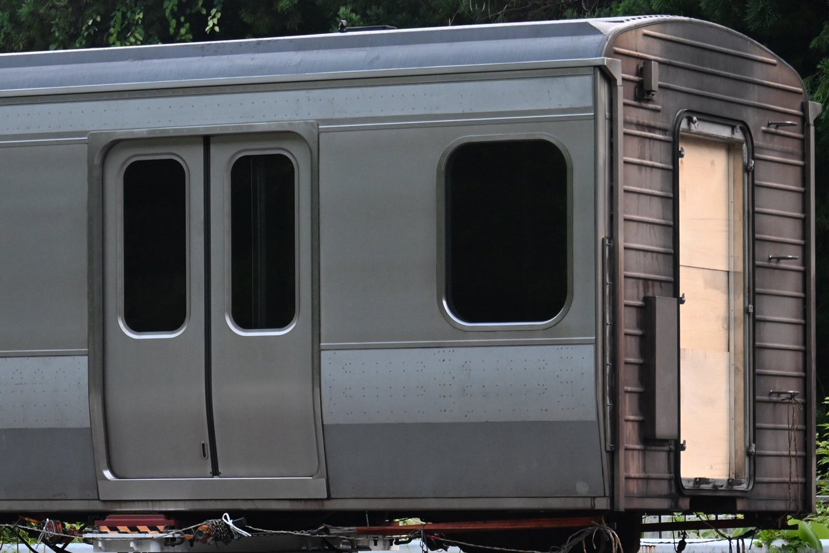 Cocoa_189_510's tweet photo. NNに長らくいた横須賀・総武快速線のE217系の中間車（モハE216-2080）ですが、陸送で昨夜搬出。

スカ色の帯を剥がされたり冷房装置等の部品が外されてたりと大きな変化も、○○とかの試験用に使用予定？

745両も製造されたE217系はこの1両を除き全車解体済、唯一の残存車に。（※山奥の某所で確認） https://t.co/XH4JnG2o6d