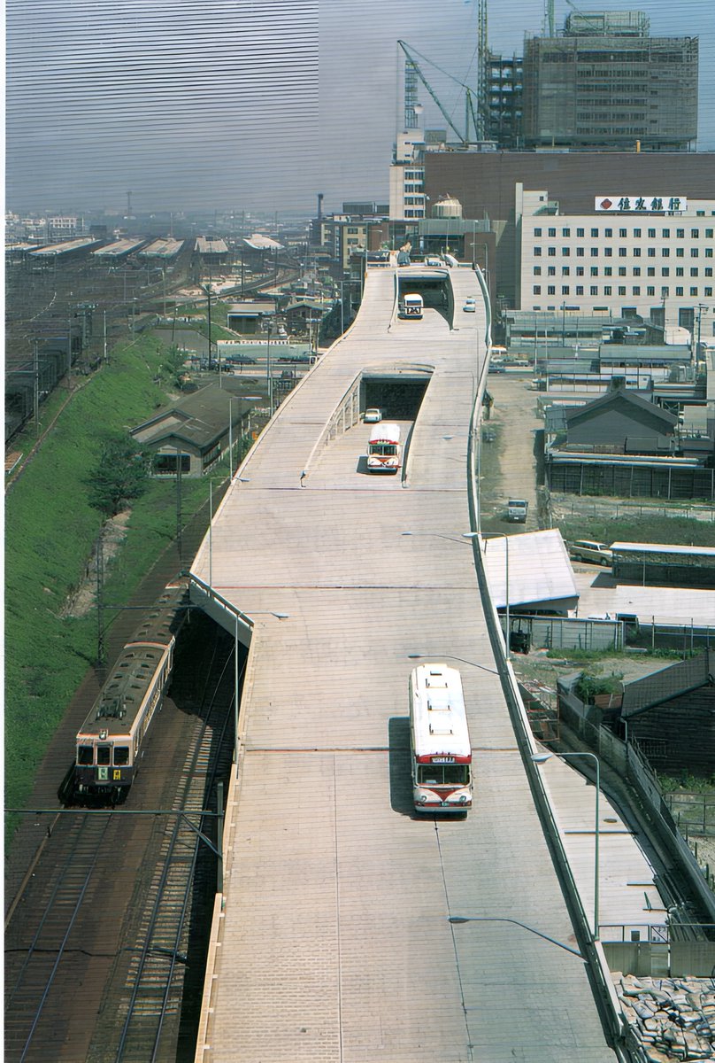 rei2012com's tweet photo. 開業当時（1967年）の名鉄バスターミナルビル
今ではビルなどに囲まれているが、平屋の建物が残っています。
ビルの3・4階にバスが発着する珍しい構造で「東洋一」と言われました。
新名古屋駅に入線中の電車（3700系？）のカラーやバスも時代を感じさせます。
今春閉鎖の予定でしたが、再開発の計画見直しで当分残るようです。