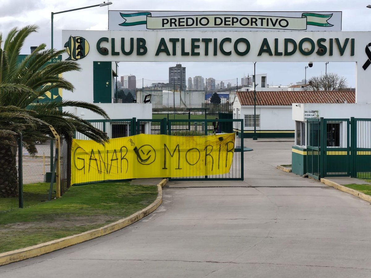 LVDEMDQ's tweet photo. 🚨🔰 Hinchas de Aldosivi se acercan al predio a pedirle al equipo que gane 

El Tiburón se encuentra en la zona de descenso. "GANAR O MORIR", es uno de los fuertes mensajes que expresan las banderas.

#Aldosivi https://t.co/DO6fP2RnSz