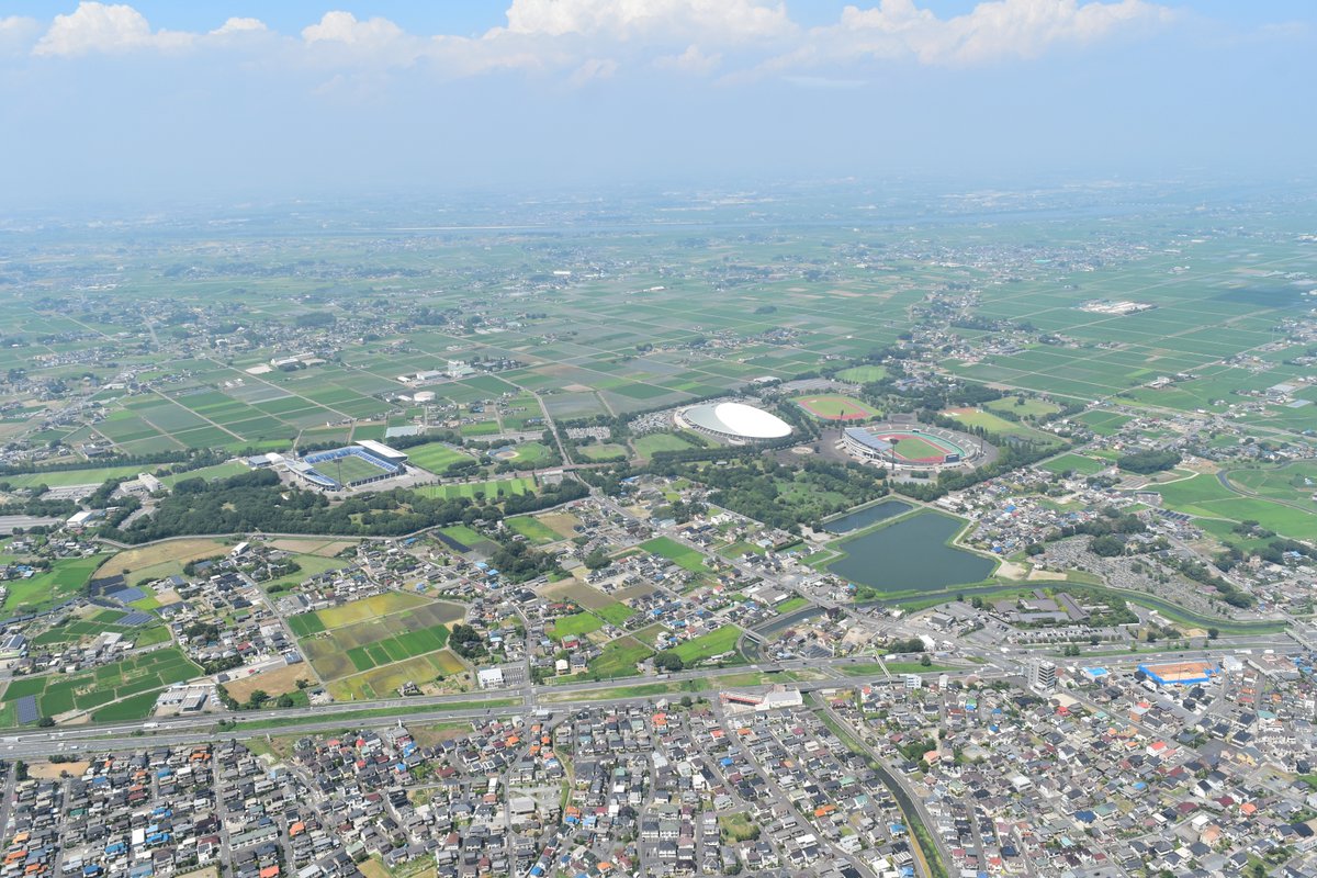 sakitama_museum's tweet photo. 埼玉の空から2026夏④🚁         
目的地２か所目へ向かう空から📷
写真中央は熊谷スポーツ文化公園です。公園整備の際に弥生時代～平安時代までの集落跡、北島遺跡が見つかりました。手前に写る国道17号バイパスの南は上之の住宅街、熊谷スポーツ文化公園の奥には利根川も見えます。 🏉🔷⚡⚔ https://t.co/SXQfGExfeB