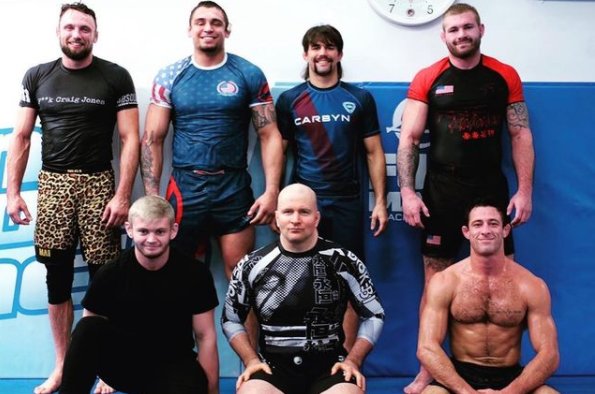 rfatsta's tweet photo. BJJ'in Einstein'i: JOHN DANAHER

John Danaher, modern Brazilian Jiu-Jitsu ve submission grappling tarihinin en etkili antrenörlerinden biri. İlginç olan şu: Danaher aslında klasik anlamda büyük bir yarışmacı değil; felsefe eğitimi almış, akademik düşünce yapısına sahip bir öğretmen olarak jiu-jitsu'ya girdi ve zamanla Gordon Ryan, Garry Tonon, Craig Jones, Nicky Ryan, Eddie Cummings ve Georges St-Pierre gibi isimlerin gelişiminde rol oynadı. 

Onu özel yapan şey yalnızca iyi teknikler öğretmesi değil. Jiu-jitsu'yu bir "teknikler koleksiyonu" olmaktan çıkarıp birbirine bağlı sistemler bütünü olarak düşünmesi. Özellikle leg-lock, back attack ve submission sistemlerinin modern grappling'e yerleşmesinde çok büyük etkisi oldu.

1. John Danaher kimdir?

John Bernard Danaher, 1967'de Washington D.C.'de doğdu ve Yeni Zelanda'da büyüdü. Columbia University'de felsefe eğitimi aldı; özellikle felsefe ve akademik düşünce dünyasında ilerledi. Ancak üniversite yıllarında geçimini sağlamak için New York'ta güvenlik görevlisi/bouncer olarak da çalışıyordu. 

Jiu-jitsu'ya oldukça geç başladı.

Yaklaşık 28 yaşındaydı.

Bu önemli çünkü BJJ'de birçok üst düzey sporcu çocukluk veya ergenlik döneminde başlarken Danaher yetişkin olarak başladı. Kendi anlatımına göre ilk dönemlerinde dövüş sanatlarına karşı oldukça farklı bir bakış açısı vardı ve jiu-jitsu ile tanışması biraz tesadüfi gerçekleşti. 

Onun hayatındaki dönüm noktası:

Renzo Gracie.
Danaher, New York'taki Renzo Gracie akademisine girdi ve Renzo'nun öğrencisi oldu.

Danaher, beyaz kuşaktan siyah kuşağa kadar Renzo'nun öğrencisi olarak kaldı ve kendi anlatımına göre hiçbir zaman başka bir hocaya geçmedi. 

Bu ilişki onun bütün kariyerinin temelini oluşturdu.

2. Danaher neden yarışmacı olarak ünlü olmadı?

Burada önemli bir ayrıntı var.

Danaher'in profesyonel yarışma kariyeri yok denecek kadar sınırlı.

Bunun önemli sebeplerinden biri ciddi kalça ve bacak problemleri yaşamasıydı. Bu nedenle kendisini aktif bir yarışmacı olarak değil, daha çok öğretmen ve araştırmacı olarak geliştirdi. 

Bu yüzden Danaher'in hikâyesi:

"Harika bir şampiyon oldu, sonra antrenörlüğe geçti."

hikâyesi değil.

Tam tersine:

"Kendi vücudu yarışmacı olmasına izin vermedi ve bunun yerine dövüş sanatını analiz etmeye, öğretmeye ve sistemleştirmeye yöneldi."

Bu da onun en büyük avantajlarından birine dönüştü.

3. Felsefe eğitimi neden bu kadar önemli?

Bence Danaher'i anlamanın anahtarı burası.

Danaher jiu-jitsu'yu genellikle şöyle düşünmüyor:

"Şu pozisyonda şu hareketi yap."

Onun yaklaşımı daha çok:

"Bu pozisyon neden oluştu? Rakibin amacı ne? Benim amacım ne? Rakibin hangi reaksiyonları mümkün? Her reaksiyona karşı hangi cevabı verebilirim?"

şeklinde.

Kendi röportajlarında akademik geçmişinin öğretme biçimini ciddi şekilde etkilediğini açıkça anlatıyor. Akademik ortamda karmaşık fikirleri parçalara ayırarak öğretmesinin jiu-jitsu eğitimine doğrudan geçtiğini söylüyor. 

Bu yüzden Danaher'in dersleri bazen BJJ dersinden çok felsefe/mühendislik dersi gibi algılanabiliyor.

4. Danaher'in jiu-jitsu anlayışı

Danaher'in en önemli fikri:

"Jiu-jitsu bir sistemdir."
Örneğin klasik BJJ'yi kabaca şöyle sıralıyor:

Rakibi yere indir.

Guard'ını geç.

Dominant pozisyon elde et.

Submission yap.

Bu sistemde hareketler birbirine bağlıdır.

Danaher'in yaptığı şey ise:

Bu büyük sistemi daha küçük sistemlere ayırmak.

Örneğin:

Leg-lock sistemi

Back attack sistemi

Front-headlock sistemi

Kimura sistemi

Armbar sistemi

Triangle sistemi

Takedown sistemi

Pinning/control sistemi

Sonra bunları birbirleriyle bağlantılı hale getirmek.

Yani:

System → Subsystem → Connection → Reaction → Counter

mantığı.

Danaher bunu yıllar içerisinde özellikle öğrencileri üzerinde test etti. 

⬇️