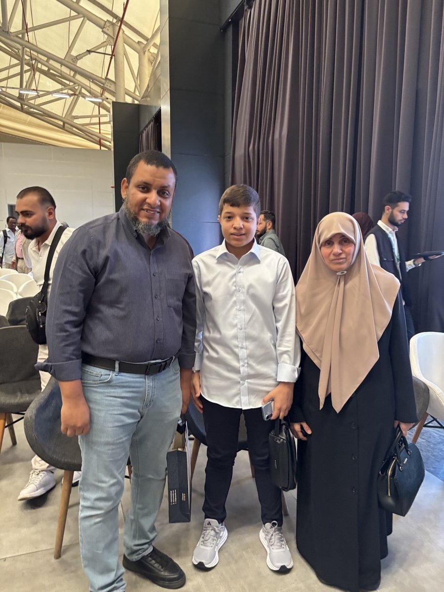 melhamy's tweet photo. أحسن ما استفدناه من معرض اسطنبول للكتاب العربي هذا العام، لقاء هذا الجبل: أم الشهداء، أم أسامة الحية.. 

وكان ذلك في المؤتمر الذي عقدته "هيئ�� علماء فلسطين"، لإطلاق مشروعها حول طباعة الرسائل ال��لمية للشهداء.. وهم في هذا المؤتمر أطلقوا ثلاثة كتب من المشروع، هي:

1. الأرض المقدسة في اليهودية والنصرانية والإسلام - لحبيب القلوب وطبيب الآذان ومن كان صوته يلذ لأسماع الأمة كلها، حبيبنا الملثم!

2. أصول الحرب العسكرية في السنة النبوية - لأسامة الحية، وتلك كانت رسالته التي نال الشهادة قبل إكمالها، فرتب أستاذه المشرف عليه صدورها!

3. تحت راية الطوفان، وهو كتاب الشهيد الذي رفع الله ذكره محمد زكي حمد، وكان هذا الكتاب سجلا لخواطره وتأملاته في أيام الحرب الأخيرة.

وقد حضرت المؤتمر اتفاقا فتفضل الإخوة في هيئة علماء فلسطين ومنحوني الكلمة الأولى، فكانت مفاجأة، فألقيت كلمة مرتجلة بما أسعف الخاطر.

ثم ألقت أم أسامة كلمة مؤثرة غاية التأثير، جزاها الله كل الخير، وجعل صبرها وثباتها ورضاها في ميزان حسناتها..

ثم استأذنتها فغنمت هذه الصورة، معها، وبيننا عبد الرحمن بن الشهيد أسامة، وقد صار فتى من بعد ما خلَّفه أبوه طفلا!

وفي مثل هذه المواقف أشعر حقا بمعنى قول القائل "النظر في وجوه الصالحين عبادة"، فهي تذكر بالله وترقق القلب وتزهد في الدنيا وترغب في الآخرة..

ومقابلها ذلك الدعاء الذي ورد في قصة جريج العابد، وهي في صحيح البخاري، "اللهم لا تُمِتْه حتى ينظر في وجوه المومسات"..

ولعله من مآسي هذه الأمة وعقوباتها أنها تنظر ليلا ونهارا في وجوه المومسات (اللاتي صار اسمهن: الفنانات)، ويغيب عن ناظريها في وسائل الإعلام أولئك الصالحون والصالحات.