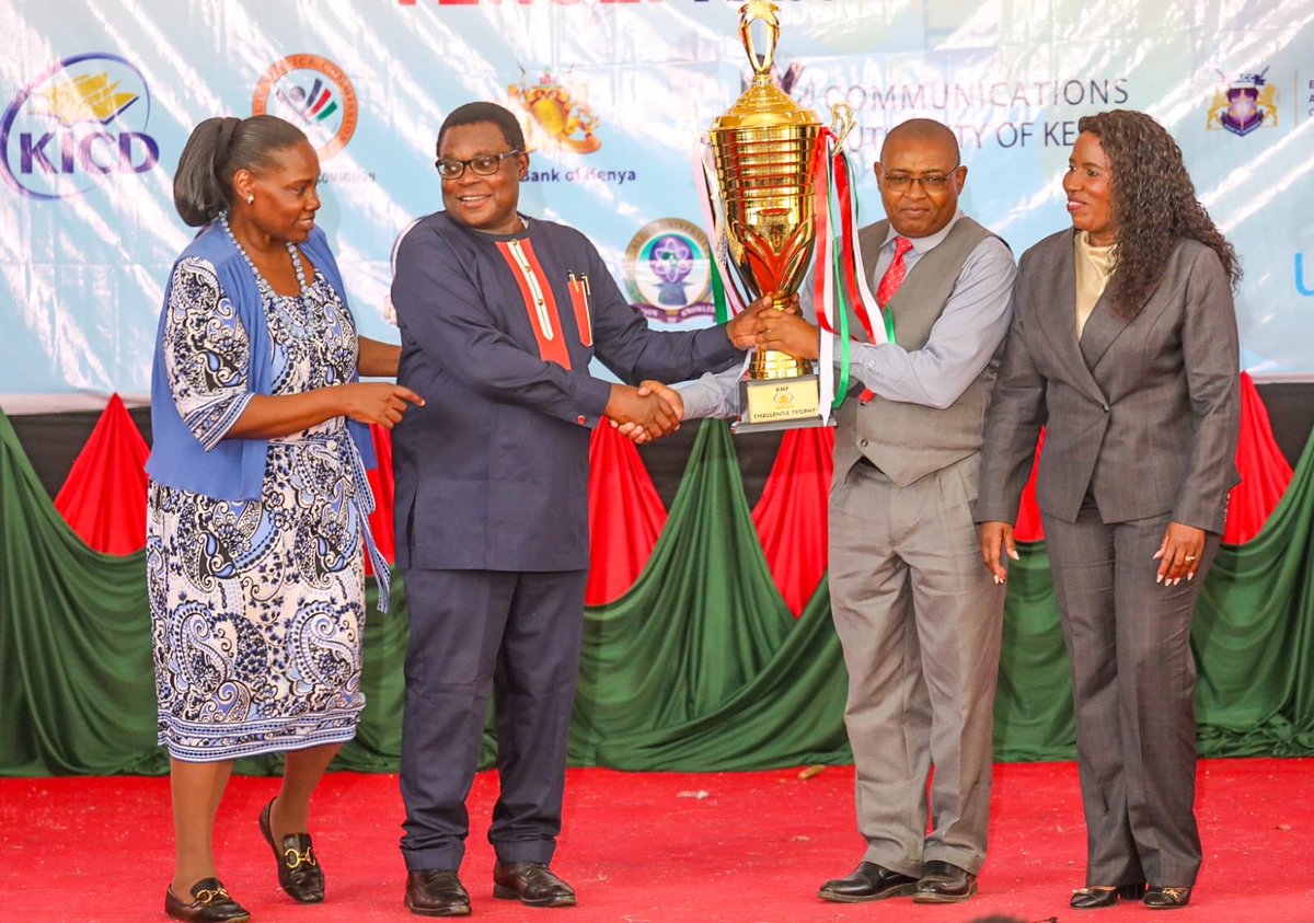 CBKKenya's tweet photo. H.E. Rt. Hon. Kenneth Lusaka, Governor of Bungoma County, and Dr. Beatrice Inyangala, Principal Secretary, State Department for Higher Education and Research, Ministry of Education, present the trophy for Best in CBK Kiswahili Class to Elegant Spur Preparatory School at the #KMF https://t.co/1dGI7nVBPl