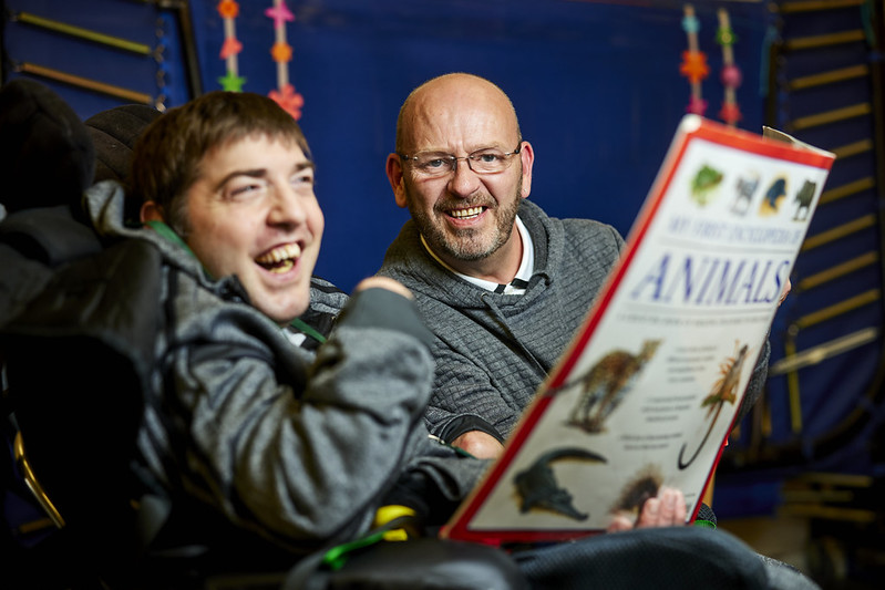 Two people are smiling and looking at an open book titled "Animals."