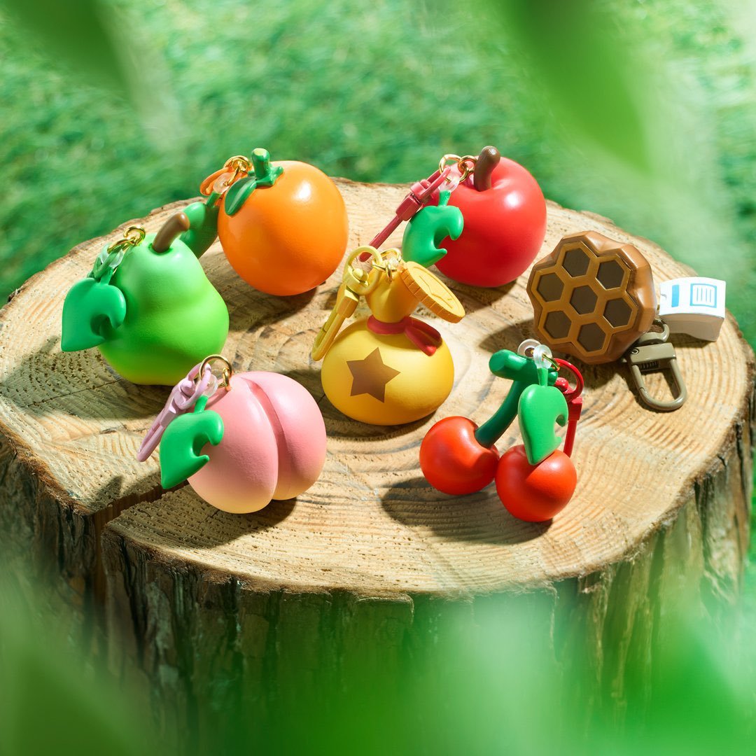 ACWorldBlog's tweet photo. An Animal Crossing Fruit Keychain gacha collection is coming to Japanese Nintendo stores in September with all 5 main fruits, a bell bag, and a wasp nest! 🎉 Look at the medicine charm on the nest!! 😭 https://t.co/nRrtxOIYFj