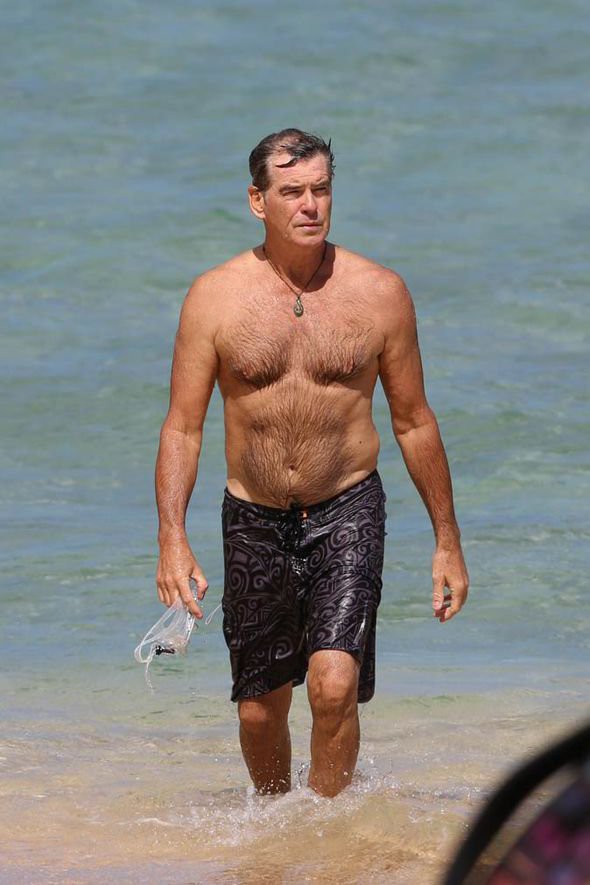 Francoballer1's tweet photo. Topless Pierce Brosnan has a James Bond moment as he flaunts his physique in Hawaii .

The beach becomes Pierce Brosnan’s own Bond-style playground as he enjoys the Hawaiian sunshine shirtless and looking effortlessly relaxed. In these photos, he is seen walking through the clear shallow water in patterned swim shorts, sunglasses, and his signature necklace, giving the whole scene a classic tropical getaway feel.
The first image captures him on the move, with his casual stride and confident posture creating an unmistakably laid-back, action-hero vibe. In the second, he walks out of the ocean with the waves around his legs, highlighting his naturally athletic build and relaxed beach style. Rather than looking overly posed, the photos have an candid quality that makes the moment feel like a glimpse of a Hollywood star simply enjoying his time by the sea.
With the tropical greenery, sparkling water, sunglasses and confident presence, it's easy to see why the images evoke memories of the timeless James Bond persona—only this time, the mission appears to be enjoying paradise