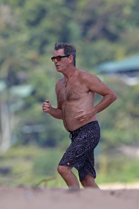Francoballer1's tweet photo. Topless Pierce Brosnan has a James Bond moment as he flaunts his physique in Hawaii .

The beach becomes Pierce Brosnan’s own Bond-style playground as he enjoys the Hawaiian sunshine shirtless and looking effortlessly relaxed. In these photos, he is seen walking through the clear shallow water in patterned swim shorts, sunglasses, and his signature necklace, giving the whole scene a classic tropical getaway feel.
The first image captures him on the move, with his casual stride and confident posture creating an unmistakably laid-back, action-hero vibe. In the second, he walks out of the ocean with the waves around his legs, highlighting his naturally athletic build and relaxed beach style. Rather than looking overly posed, the photos have an candid quality that makes the moment feel like a glimpse of a Hollywood star simply enjoying his time by the sea.
With the tropical greenery, sparkling water, sunglasses and confident presence, it's easy to see why the images evoke memories of the timeless James Bond persona—only this time, the mission appears to be enjoying paradise