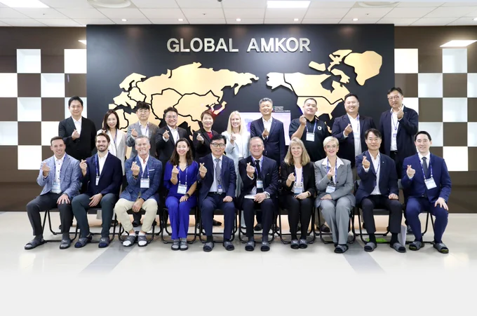 Arizona and Amkor representatives gather for a group photo in front of a Global Amkor display.