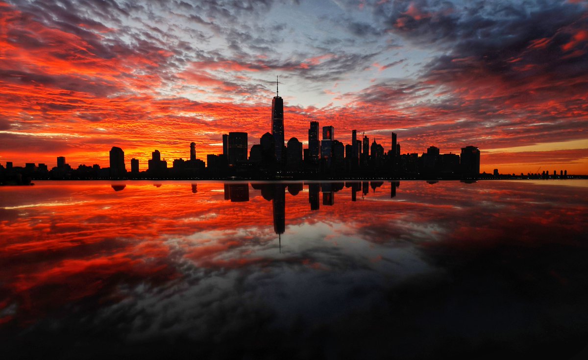 GaryHershorn's tweet photo. Lower Manhattan and One World Trade Center are reflected on the top of a 9/11 Memorial in Jersey City, New Jersey as the sun rises in New York City, Sunday morning #newyorkcity #nyc #newyork #sunrise https://t.co/qERsthvNxU