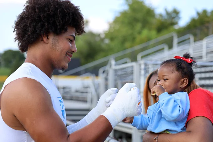 football player fistbumps toddler