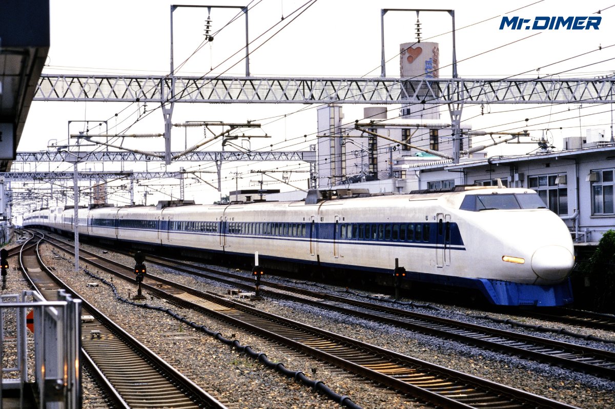 MrDIMER_X's tweet photo. 【試作車の特徴？】"目つきが鋭い"100系のお話

100系といえば、
0系の丸みを帯びた姿から一転、
細長い前照灯と「シャークノーズ」による
精悍な顔立ちが特徴の新幹線電車、でした。

しかし――
同じ100系でも、
よく見ると妙に「目つきの鋭い」車両が存在しました。

100系の試作車として製造された
9000番台・X0編成のことです。

1985年に登場したX0編成は、
後の量産車とは細かな部分が異なっており、
そのひとつが前照灯。

試作車では前照灯が
量産車よりも強く傾斜しており、
正面から見ると明らかに「つり目」。

一方、量産車ではこの角度が緩められ、
私たちがよく知る100系の
やや穏やかな表情となりました。

違いは目だけではありません。

X0編成には、
量産車より小さな客室窓が並ぶほか、
先頭車の細部や扉配置などにも
試作車特有の仕様が存在しました。

その後、X0編成は量産化改造を受けて
「X1編成」となりますが、
この特徴的なつり目の前照灯は残されました。

つまり100系が活躍していた時代、
編成番号を知らなくても、

「なんだかこの100系、目つきが鋭いぞ」

と感じたなら、
それは元・試作車のX1編成だった可能性が高いわけです。

一見ほとんど同じに見える100系。

しかし顔つきを見れば、
たった1編成しか存在しなかった
試作車の面影を見分けることができました。

その後、
量産車の登場、営業運転での実績を受け、
本編成も"量産化改造"を受けることになりますが、
これにより消えていった「試作車らしさ」は、
表情に残されていたのです。

（Mr.DIMER編集長）