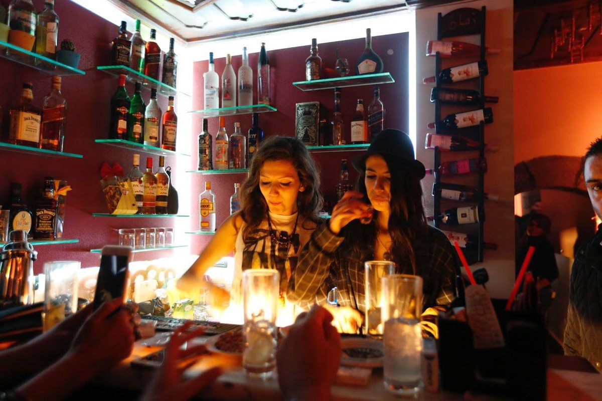 kunley_drukpa's tweet photo. ABOUT SYRIA’S NIGHTLIFE 🇸🇾

My experience is that Syria was like this too under Assad - think you have to appreciate Syria has always had a class of people like this and that the tension between secular westernised Syrians and religious conservative Syrians is one of the main drivers of conflict in the country. When I visited Syria towards the end of the Civil War under Assad one of the most surprising aspects was how active the nightlife was - and not just how active it was but how ‘good’ it was ie in Damascus at least Bars, Sisha Places and Nightclubs full of lots of well-dressed and attractive Syrians partying

The Syrian women in the different venues were almost without exception very attractive. Not to be too lewd or flippant, this is a very mature and sensible account, but this was a very striking aspect of the experience - it is genuinely quite rare to be in a place where almost all of the women around you are that attractive let alone a majority Muslim city nominally in the middle of a Civil War. Another thing too, most were visibly westernised, many with no hijabs and so on, they could have slotted straight into an Ibiza club night - something you again wouldn’t necessarily assume in Syria of all places but maybe it makes a certain kind of sense, or for the parts of Syrian society who go to these kinds of venues at least. Interesting contrast versus the ISIS British Pakistani Jihadi John or mountain goatherder types you could see around the rest of the country anyway

Often it was like being in a bar and club street in a Western country, in a Mediterranean one. Lots of dancing, smoking, drinking. People really liked taking shots. In terms of music everything from electronic, dance, house, EDM and trance to lounge, Arabic lounge and reggaeton etc and in one place even UK Grime. People often throw out the casual platitude that even in war ‘life goes on’ but there is going on and then really going on. Say what you want about Assad but they were throwing some great parties under him. Maybe it was the war that gave them a little extra special edge, who knows

Some anecdotes: 

The Syrian Australian Woman

One evening met a Syrian woman who lived in Australia in the bar

“I live in Australia I’m from Australia but I’m also from Syria”

“So you’re Syrian?”

“I’m a Syrian from Australia”

“What are you doing in Syria? Does it bother you that the war is still ongoing?”

“I fly back to Syria every year to see my family, stay in Syria a while. Recently I’ve been working on some art installations”

“Can you do that in the middle of a war?”

“Yes I’ve been do it most years when I can”

“Did it you do it the year Damascus was under siege?”

“No not that year but most other years”

“And you can genuinely just come in to Syria during the war?”

“Yeah Sydney to Dubai then to Beirut then cross the border. Sometimes they had flights to Damascus airport”

She was very insouciant about it

The Sudanese DJ

There was a Sudanese man, (not an Arab Sudanese an African (Nilotic) Sudanese,) who after fleeing the Sudanese Civil War somehow had found his way to Damascus apparently illegally and then again somehow had taken to DJing in the Damascus Nightclubs. He was very good at DJing and in his exoticness had became enough of a local celebrity that nobody really cared that he was there illegally. He would have special sets during the height of the Civil War and people would go and see ‘The Black African DJ’. There are hardly any black people in Syria despite its proximity to Africa so this was genuinely a novelty for a lot of Syrians - including the wealthier more liberal ones who went to Damascus nightclubs 

Door Checks

There aren’t just nightclubs, which is one thing, but high end nightclubs too. Was taken aback at first

“Sorry you can’t come in”

“What?”

“You’re not dressed formally enough”

Just assumed that because Syria was still in the middle of a Civil War they would be more lax about dresscode at nightclubs. Not the case