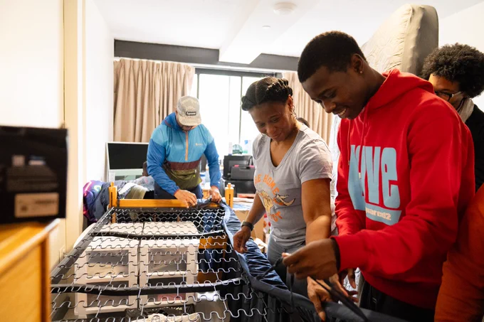 family moving in and setting up bed in a dorm room