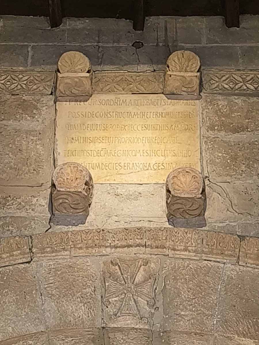 trastamara_ana's tweet photo. Según la tradición historiográfica, el monarca visigodo Recesvinto regresaba hacia Toledo tras haber sofocado una revuelta de los vascones en el norte de la península. 

Al llegar a la antigua villa romana de "Balneos" (actual Baños de Cerrato), se encontraba gravemente enfermo debido a una afección renal severa (posiblemente cólicos nefríticos).

Los lugareños le ofrecieron beber agua de un antiguo manantial que ya había sido utilizado en época romana por sus propiedades termales y medicinales. 

Al beberla, el dolor del rey remitió de inmediato. En señal de profunda gratitud por su curación, que consideró un auténtico milagro, Recesvinto ordenó levantar un templo en ese mismo lugar bajo la advocación de su santo patrón: San Juan Bautista.

A diferencia de otros templos medievales envueltos en mitos, la fundación de San Juan de Baños cuenta con una prueba física irrefutable: una inscripción de piedra original colocada sobre el arco triunfal del coro.

El texto está tallado en caracteres visigóticos (mayúsculas toscas dispuestos en seis hexámetros dactílicos) y es el documento arqueológico que permite fechar la iglesia con total exactitud. 

Las excavaciones arqueológicas modernas revelan que la decisión de Recesvinto no fue casualidad. El templo se asentó sobre una zona de fuerte arraigo religioso previo.

En el siglo XIX se descubrió en las inmediaciones un altar votivo romano dedicado a las ninfas del manantial, demostrando que el lugar ya era un santuario de sanación precristiano.

Para levantar el nuevo templo cristiano, los constructores de Recesvinto reutilizaron los fustes, columnas y capiteles de las edificaciones romanas tardías que rodeaban la fuente, cristianizando por completo el espacio.

La basílica nació como una fundación directamente vinculada a la corona, pero bajo el control organizativo de la influyente Sede Episcopal de Palencia.

#ArteVisigodo
#Palencia
#HistoriadeEspaña