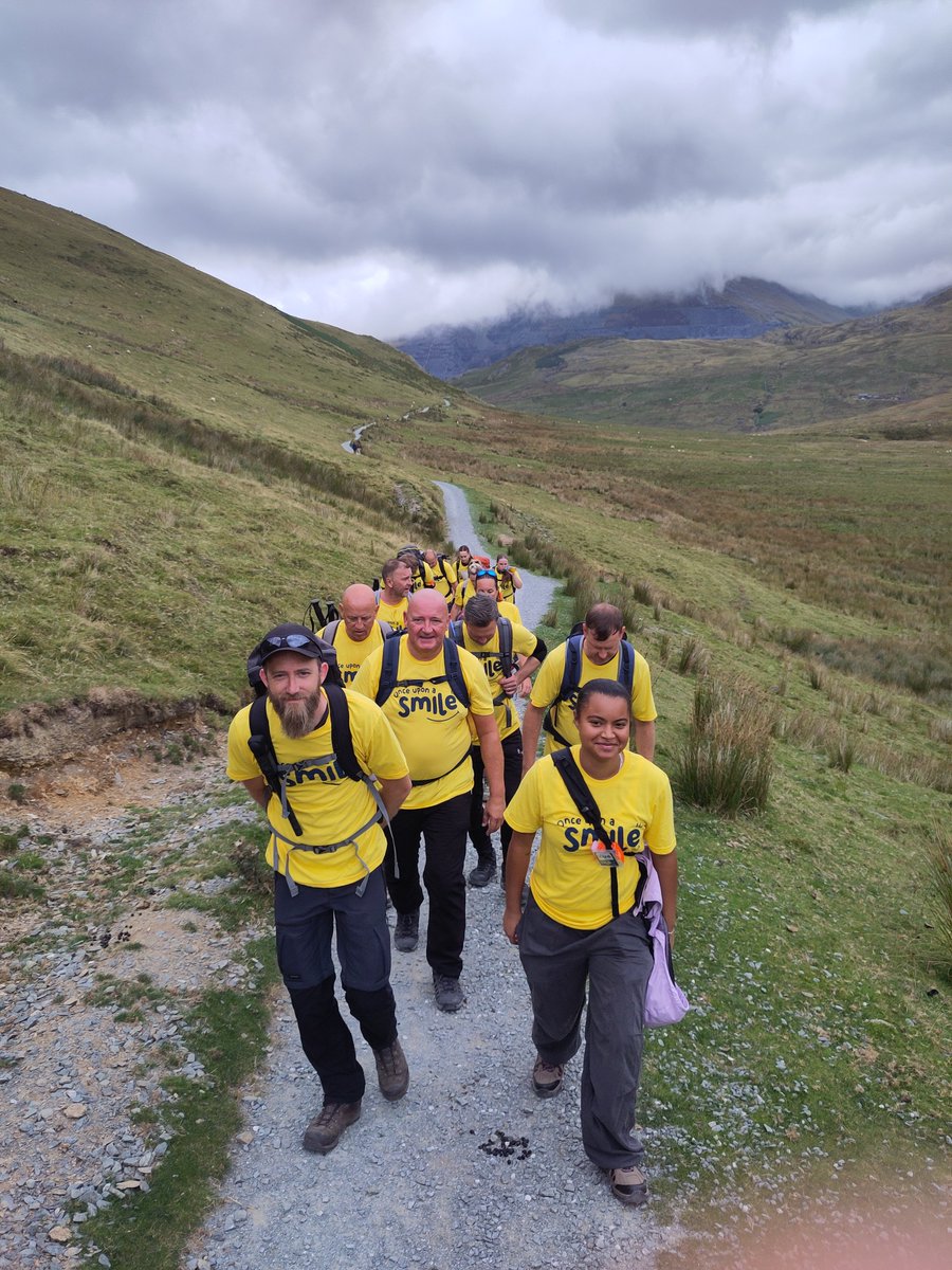 A group of people walking on a path through the hills