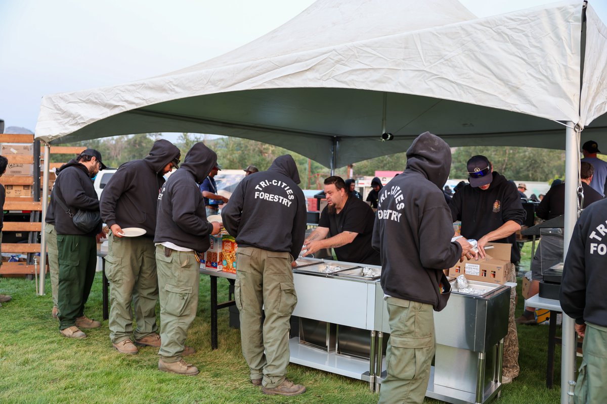 Several firefighters wait in line while staff serve them food.