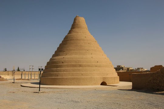 Dr_TheHistories's tweet photo. More than 2,400 years ago, Persian engineers solved a problem that wouldn't be solved again until the 19th century: how to make ice in the middle of the desert and keep it through a summer that regularly hits 40 degrees Celsius.

The structure they built is called a yakhchal. It translates, roughly, as "ice pit." The name undersells it.

From the outside, a yakhchal looks like a massive mud-brick dome, anywhere from 10 to 15 metres high, rising out of the flat desert floor. The geometry was deliberate. The dome's steep angle minimized the surface area exposed to direct sunlight. The thick walls, mixed with a waterproof mortar called sarooj, made from clay, sand, egg whites, goat hair, and ash, were nearly impermeable to heat. Engineers had worked out an effective insulating compound without knowing the word "insulation."

Below ground was the real machinery: a deep storage chamber, sometimes large enough to hold several tons of ice, carved into the earth where temperatures stayed stable even in the peak of summer.

But the yakhchal didn't just store ice. It also made it.

In winter, workers diverted water from nearby qanats, the underground irrigation channels that were themselves one of antiquity's great engineering achievements, into shallow pools beside the structure. The desert night sky, in an arid climate with little humidity, radiates heat into space with unusual efficiency. On cold clear nights, even when air temperatures barely dipped below freezing, the shallow water lost enough heat to the sky that it froze.

That ice was cut, carried into the underground chamber, and packed with insulating material.

Shading walls, often running east to west, protected the pools and the structure's north-facing entrance from direct sun throughout the day. The entire complex was oriented around shadow.

By the time summer arrived, the yakhchal held a reserve that could supply chilled drinks and chilled food to royal courts and urban markets for months. Faloodeh, a chilled dessert made with frozen rose water and starch, was served from yakhchal ice. So were chilled drinks offered to Persian nobles during audiences that would have been, without this system, simply intolerable.

Roughly 100 to 150 yakhchals survive in Iran today, mostly in the arid central and eastern regions around Yazd and Kerman. They are still standing. The sarooj mortar has outlasted most of what the modern world has built in the same interval.

The Achaemenid Empire, which commissioned many of these structures, fell to Alexander in 330 BCE. The yakhchals kept working anyway.

No electricity. No refrigerant. No moving parts.

Just geometry, the right mortar, and a precise understanding of how a desert sky loses heat on a winter night.

The sarooj mortar formula, clay, sand, egg whites, goat hair, ash, has survived long enough that modern materials scientists have studied it. Some of them came away genuinely impressed by the impermeability.

#drthehistories