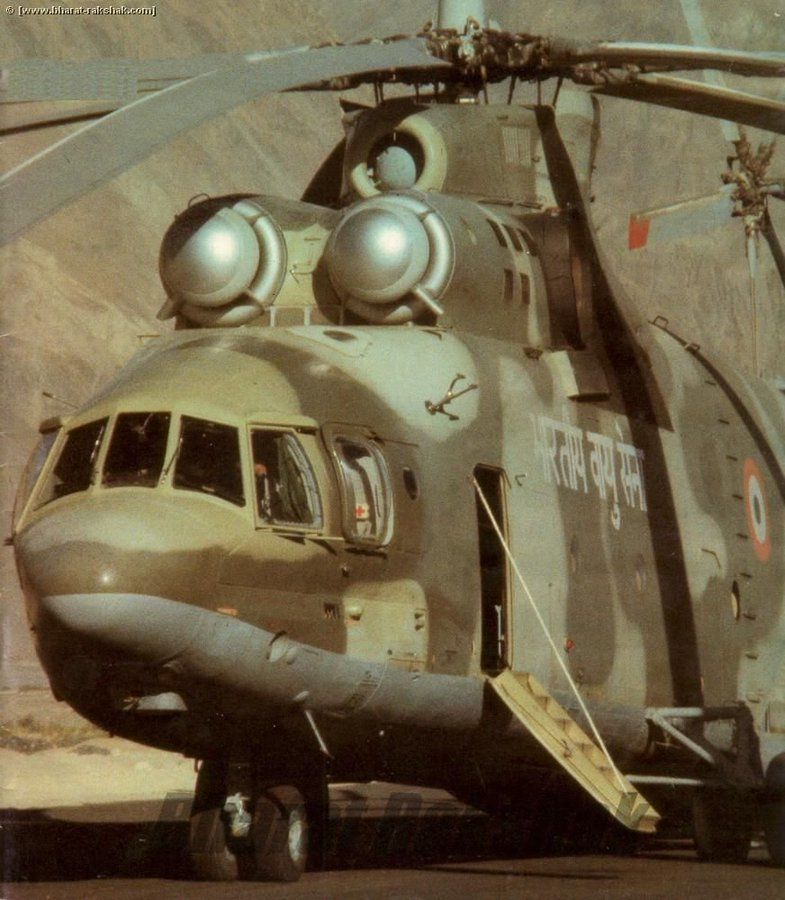AnchitGupta9's tweet photo. My rants on Kargil would be incomplete without the Mi-26, and particularly without one extraordinary sortie flown on the night of 26 May 1999. The air campaign was only hours old.

By that evening, Srinagar faced a shortage of the 57 mm rockets required by its armed Mi-17s. Replacement stocks were available at Adampur and Pathankot, but they had to be moved into the Kashmir Valley without delay.

The task fell to No. 126 Helicopter Flight at Chandigarh, then operating the IAF’s only heavy-lift helicopter. On paper, the Flight had four Mi-26s. In practice, it had only one aircraft available.

Two Mi-26s were aircraft on ground. A third had gone to Russia for a major overhaul, with three members of the crew also away. The available flying establishment was equally thin.

Squadron Leader Jang Veer Singh Guron was qualified for operations on the Mi-26 by day, but was not current for night flying. Another pilot was new to the unit and had completed only his day conversion. The incoming Commanding Officer was not current on type. The available flight engineer had only recently completed his initial training, while the electronic operator had limited experience on the aircraft.

Guron himself had been on leave in Lucknow when Group Captain H.P.S. Natt, then at Western Air Command, called and instructed him to return immediately. He reported at Chandigarh barely two or three days before Operation Safed Sagar began.

Nor was the Flight’s sole available Mi-26 fully healthy. The helicopter had separate transducers for indicating the main-rotor RPM and the high-pressure compressor RPM. Two were required. Only one was serviceable.

This meant that, during a sortie, the crew could monitor one of the two parameters, but not both. It was a deficiency they had agreed to operate with. The transport fleet was already heavily committed, and there were loads for which no lighter helicopter was an adequate substitute.

On 26 May, Guron returned to Chandigarh and then routed through Adampur and Pathankot to collect the rockets. He reached Pathankot at approximately 1400 hours.

Loading ammunition into the cavernous hold of the Mi-26 was a slow process. By the time the load had been secured and the helicopter was ready to depart, daylight had gone. The aircraft was also loaded beyond its rated capacity.

The situation confronting Guron was therefore stark. He was to fly an overloaded Mi-26 into the Kashmir Valley at night, without being current for night operations, in an aircraft in which one of the two vital RPM indications could not be monitored.

Group Captain Natt gave him the clearance to proceed. The normal helicopter route towards Srinagar wound through the valleys. It was also considerably longer. With the aircraft carrying an excessive load, fuel had become the governing consideration.

The alternative was a direct route across the mountains and over the Banihal Pass. It saved distance and fuel, but exchanged the relative security of the valley route for a high crossing of Banihal in darkness.

The expression “dark night” has a specific meaning in military aviation. A night with less than a quarter moon is classified as a dark night. The weather on 26 May was clear, but there was little natural illumination.

Guron chose the direct route.

The heavily laden Mi-26 climbed towards Banihal and crossed the pass in the darkness. On the outward flight, the high-pressure compressor RPM indication was unavailable. The crew continued across the mountains and brought the aircraft into Srinagar late that night. The 57 mm rockets had arrived. During the return flight, the main-rotor RPM gauge also failed. 

Later, the Mi-26 carried a 14-tonne BEML tractor whose dimensions almost matched the helicopter’s loading ramp. With the aircraft overheating and responding poorly in the valleys, Guron executed a roller landing at Udhampur to bring it down without striking the tail rotor.

It transported a P-18/19 surveillance radar underslung into Kargil, despite the unit having little experience of such an operation at those altitudes.

On another mission, two Army trucks filled with communications equipment were driven directly into the Mi-26 at Palam and flown north. A delay on the ground consumed precious fuel, and the warning came on fifteen minutes short of Chandigarh. The aircraft landed, refuelled and continued to Srinagar that evening.

After approximately thirty hours of intense flying, the Mi-26 itself became unserviceable.

The sortie over Banihal remained exceptional even within that remarkable sequence. Guron received an AOC-in-C Commendation.

The fighters and armed helicopters naturally dominate accounts of Operation Safed Sagar. But their effort rested upon a much larger machinery of ammunition, fuel, radars, communications equipment and engineer plant being moved forward, often at the edge of what the available aircraft and crews could manage.

Late on 26 May 1999, the IAF’s only available Mi-26 crossed Banihal in darkness carrying an overloaded consignment of 57 mm rockets.

It fired none of them. Its task was to ensure that the helicopters at Srinagar still could. That is why the Mi-26 belongs in the Kargil story.

#IAFHistory @IAF_MCC