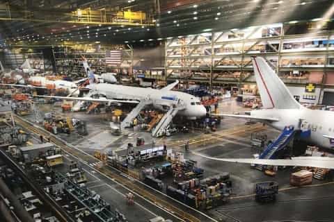 Object_Zero_'s tweet photo. Boeing Everett

This is the largest enclosed manufacturing space in the world by volume, it has its own internal weather system and micro climates inside the building. It’s about 13m cubic meters.

It was built in 1967 to build the 747 jumbo jet.

What is interesting is that Everett operates as an assembly line, that is continually move in the same way a Ford autoplant does.

Before 67, jets were assembled in batches where the aircraft would sit stationary in assembly bays and several would be built side by side in a batch. The SR-71 was built in stationary batches.

The two production types warrant different quality systems, different tooling and capex requirements. But the MAIN issue between these two types of manufacturing method is the cycle time of each assembly step at each station.

In batch production, each assembly step can be different duration. Step 35 might take 45 minutes, step 235 might take 11 minutes and step 6235 might take 5 hours. This works because every aircraft in the batch does each step concurrently, in parallel.

In continuous assembly line production, all the steps have to be the same cycle time duration. Otherwise the entire plant moves at the cadence of the slowest station and your utilisation collapses.

This is why continuous production is so hard, you have to design for piecewise assembly, and if you do not start with piecewise assembly as a starting design philosophy you’re going to have a very bad time.

Being able to design for parallel and serial assembly is a super power. Product designers too often focus on performance and too rarely do they focus on how the product is built until it’s almost time to build it.

Anyway, Everett exists, so doing things at 1,000 acre scale is perfectly doable.