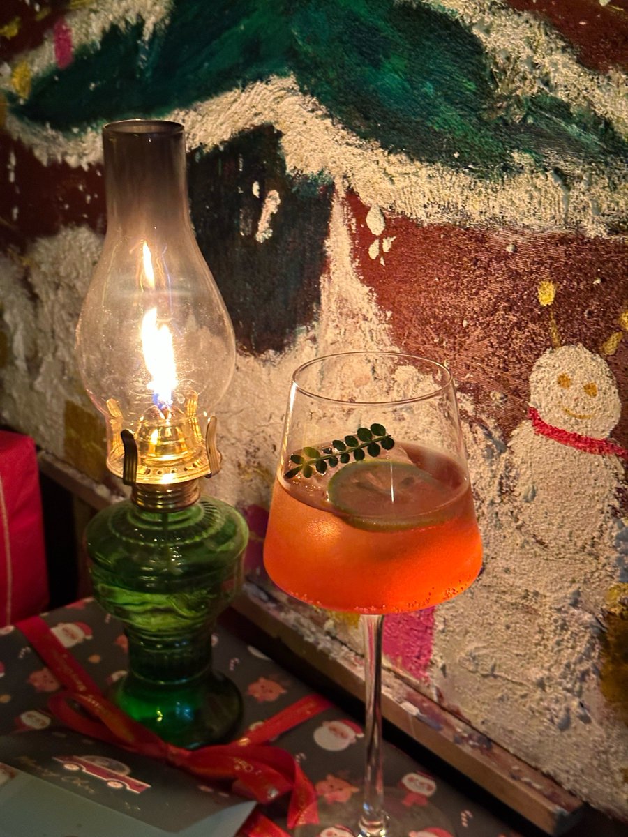 wX5kJU3tzSc6hS6's tweet photo. La luz cálida de la farola ilumina la barrera del pequeo local de noche, y una taza de chocolate caliente humea suavemente sobre la mesa de madera. https://t.co/aH653ZMgrL