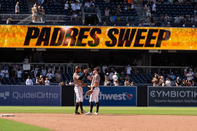 Xander Bogaerts and Jake Cronenworth celebrating after the Padres sweep. They are wearing the Padres camo uniform.