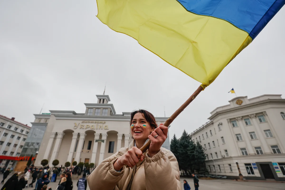 Young woman waving a large Ukrainian flag.