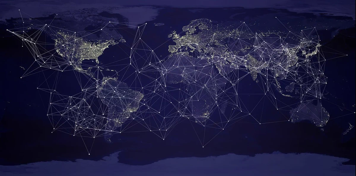 A world map at night with a glowing white geometric network of lines and nodes connecting global locations.