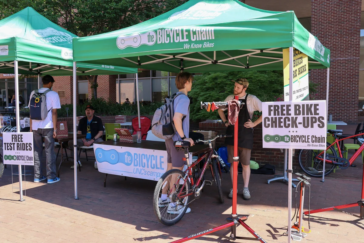 A student getting a free bike check-up from the Bicycle Chain tent at the Gear Up for Bike Month event in Davis Courtyard on April 23, 2026, hosted by Transportation and Parking.
