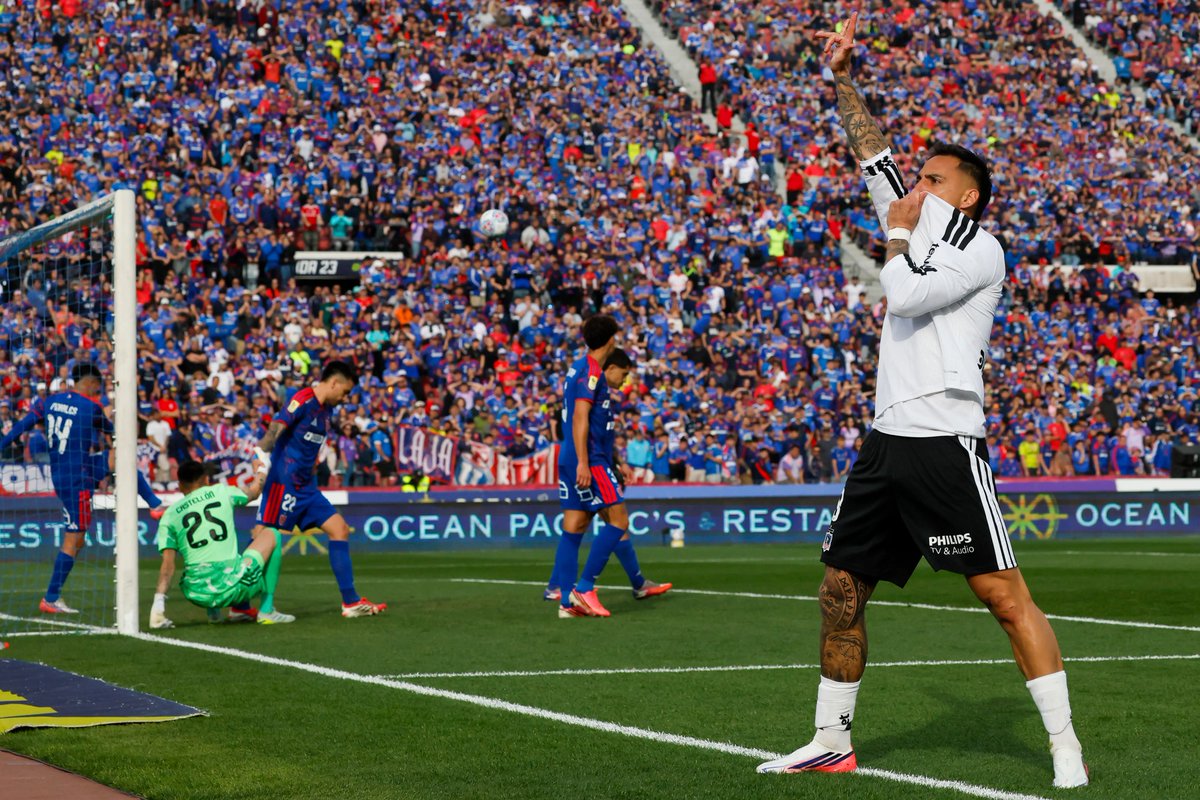 juuuliaaaaan's tweet photo. Tremenda foto de Javier Correa. Beso al escudo frente a la hinchada rival, atrás los jugadores de Universidad de Chile lamentando el gol. Arte. https://t.co/C1UL0RpK9W
