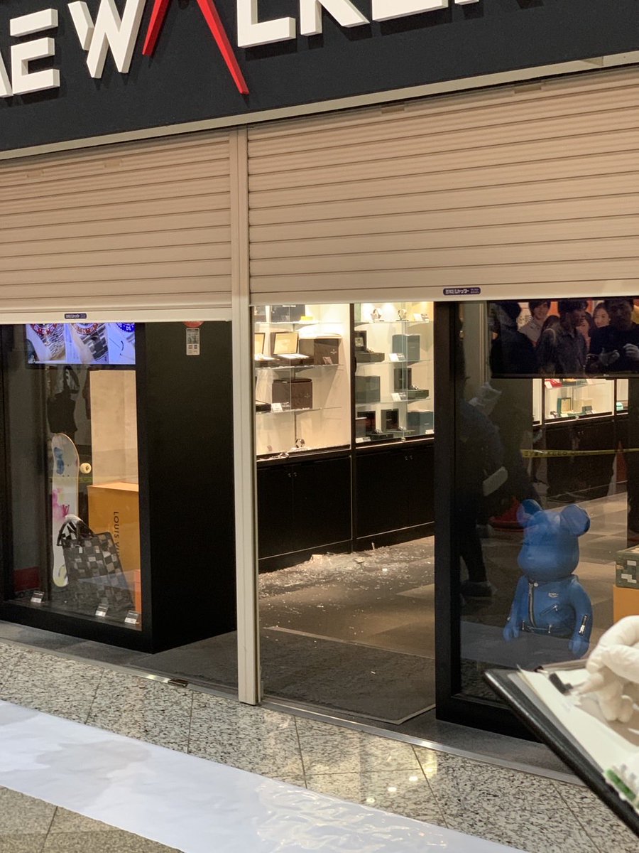 TIME WALKER店頭。シャッター半開き、割れたガラスと空のショーケース、床の破片