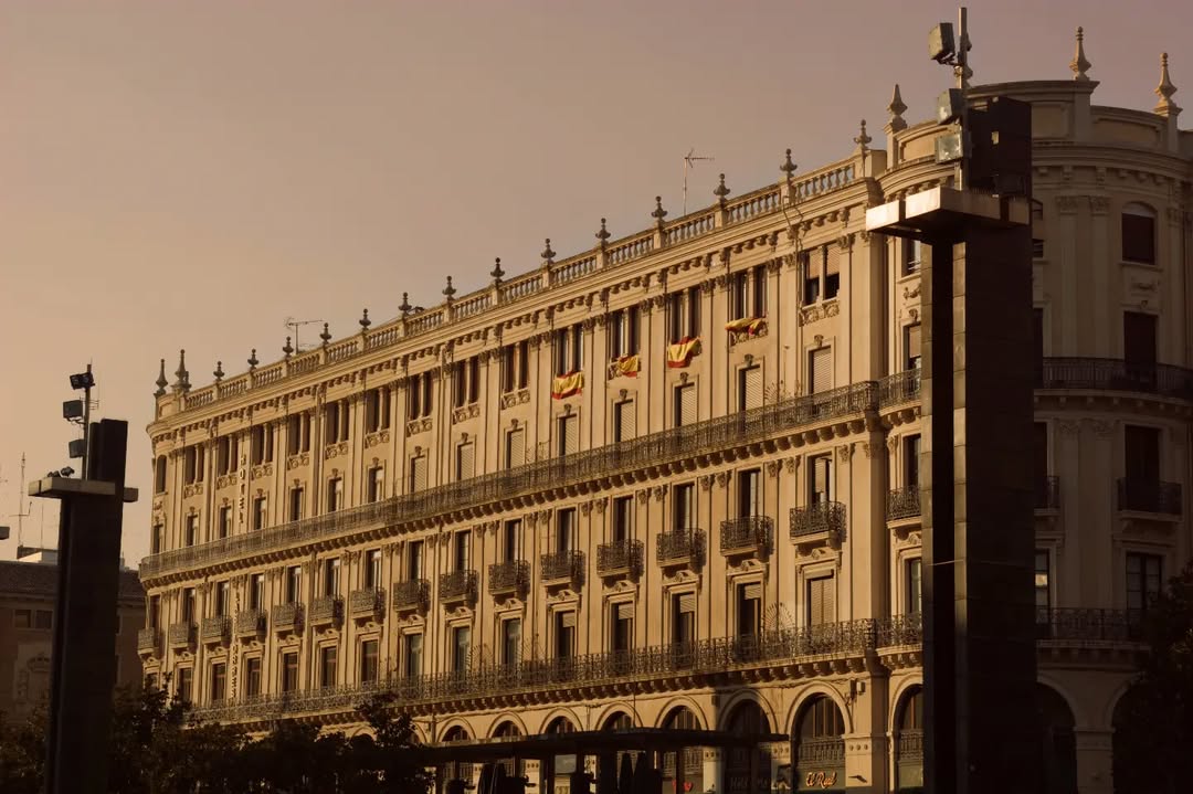 ZaragozaTurismo's tweet photo. El edificio sobre el Pasaje de la Industria y el Comercio, en plena Plaza del Pilar de #Zaragoza, en origen tenía un aspecto diferente, afrancesado por la mansarda y los remates de sus chaflanes, sustituidos por la balaustrada actual 🤓

📸 IG mario__zgz

#aquiyahorazaragoza https://t.co/kZEzT29ZDz