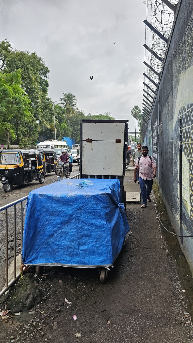 LennyDsa's tweet photo. Food carts have been dumped blocking the footpath just before Seepz metro station entry B1. Conveniently hidden by the buses parked there and chained to the fence. There is also an open manhole cover next to this. @mybmc @mybmcWardKE @MumbaiMetro3 @mumbaimatterz https://t.co/suttRdM23p