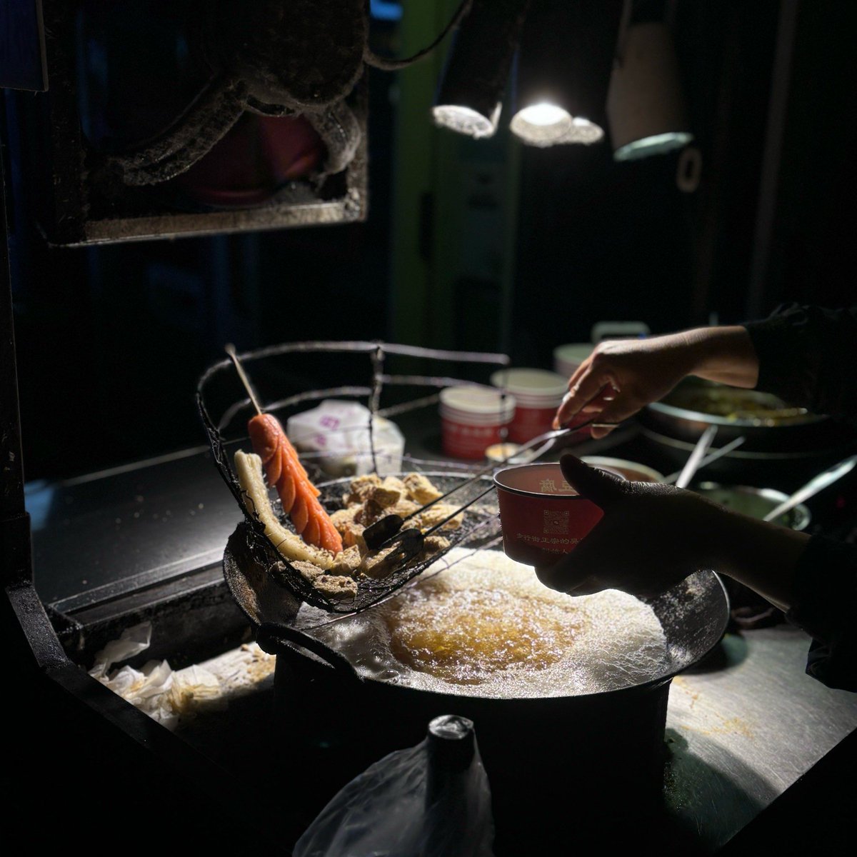 VarolZeynep's tweet photo. Late-night stall, sizzling fried squid with fragrant sesame seeds, warm congee in a small clay pot—soft glow under the red paper lantern, quiet hum of city streets outside, perfect little comfort after a long day. https://t.co/P8NXhMcIuC