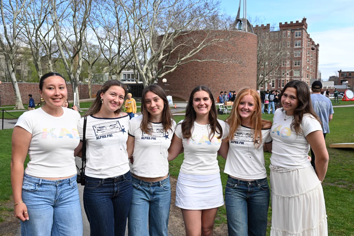 Six students wearing white shirts standing on the Kresge oval on MIT's campus.