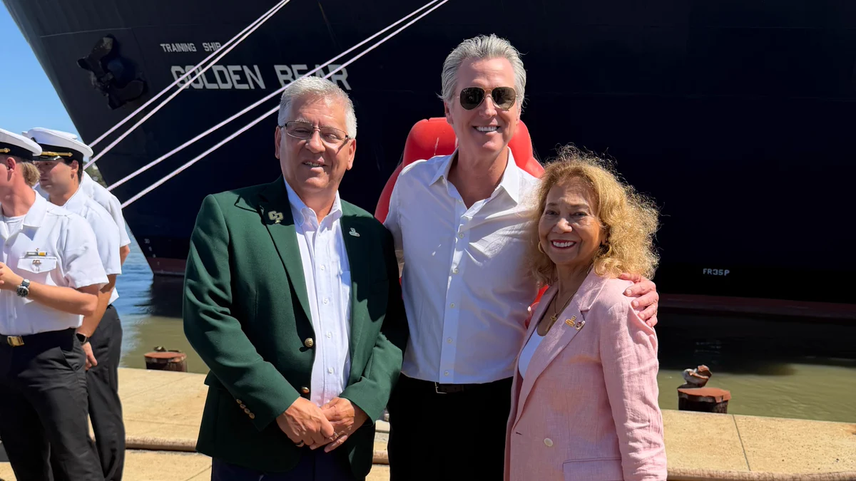 Cal Poly President Jeffrey Armstrong, Governor Gavin Newsom and CSU Chancellor Mildred García pose together in front of the Cal Poly Maritime Academy training ship Golden Bear.