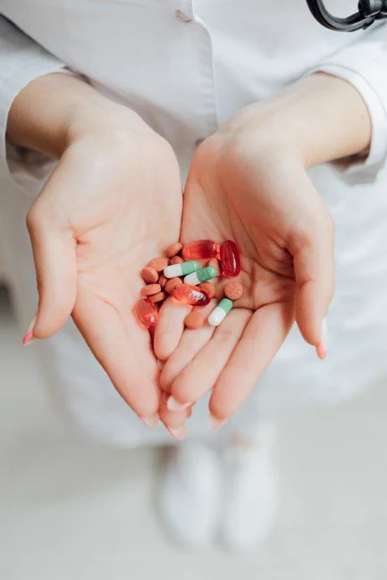 Close-up of a person holding various pills and capsules in their hands, symbolizing healthcare and medicine.