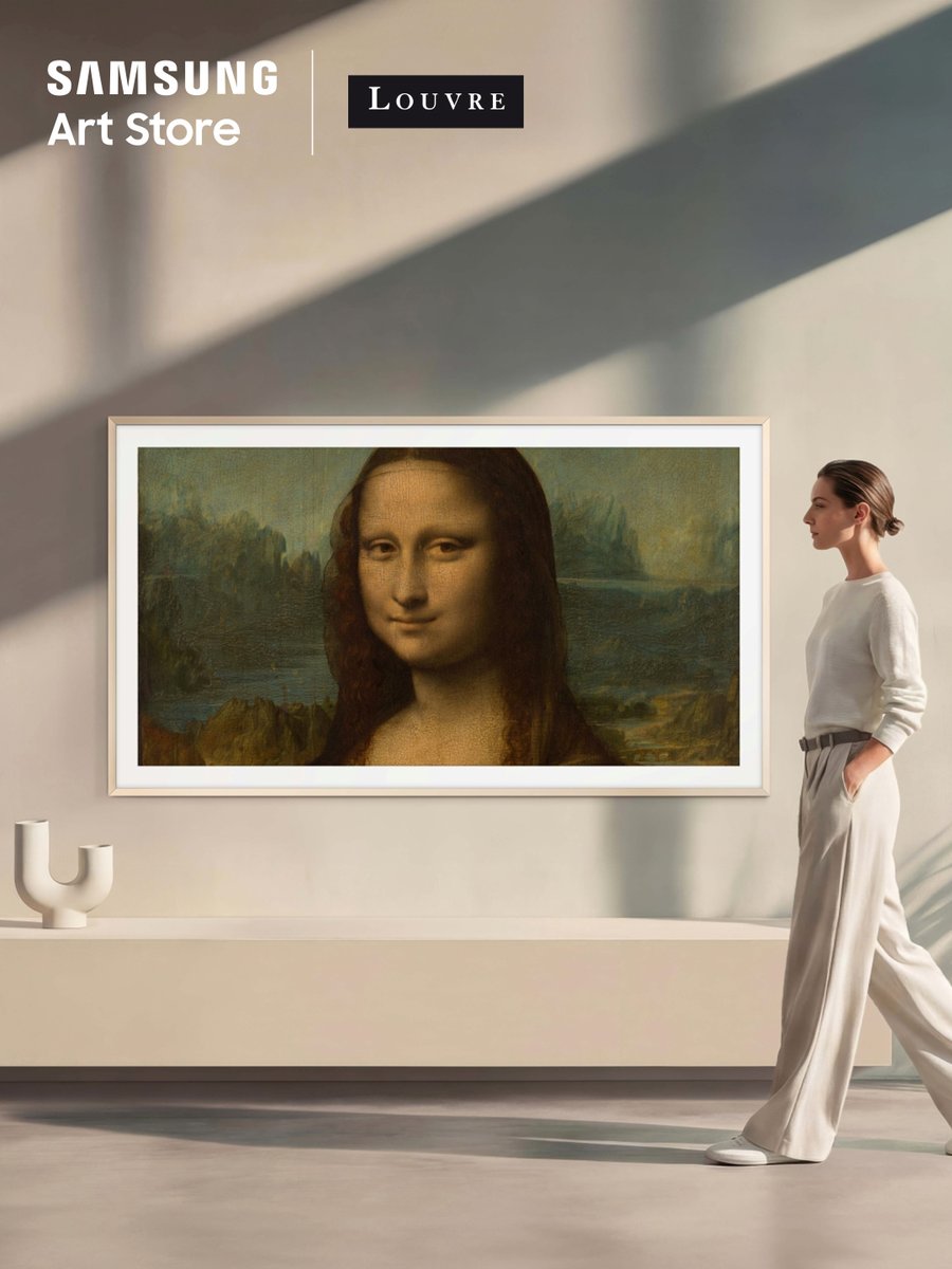 "Portrait of Lisa Gherardini, wife of Francesco del Giocondo, known as the Mona Lisa or La Gioconda" (1503–1519) by Leonardo da Vinci from the Samsung Art Store x Louvre collection displayed on Samsung The Frame, as a woman walks past in a sunlit gallery-style living room, featuring the Samsung Art Store and Louvre logos in the top left corner.