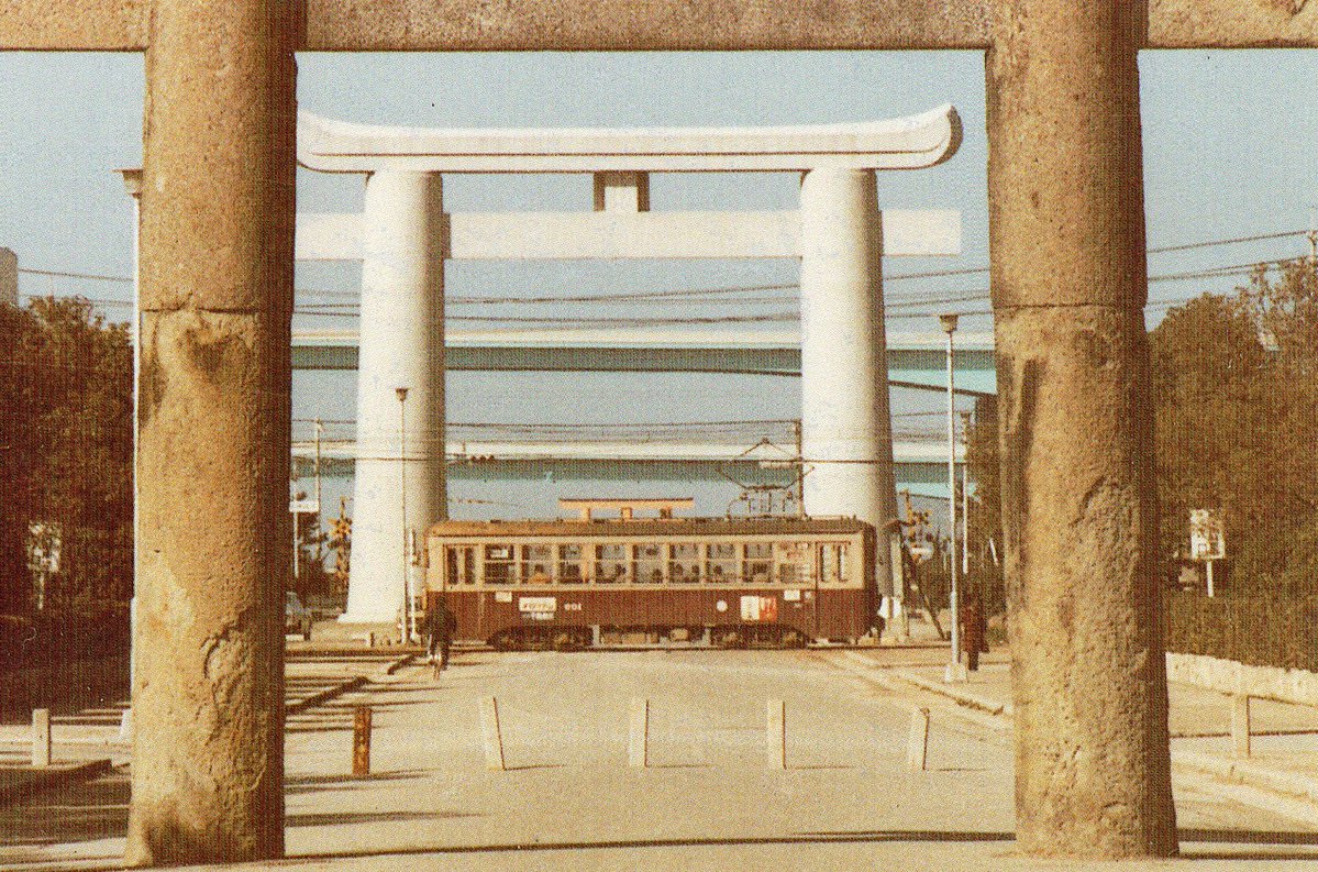 rei2012com's tweet photo. 1970年代後半頃の路面電車と筥崎宮参道。
西鉄福岡市内線の路面電車が参道を通過しています。
今はなくなった二つの鳥居（手前が三之鳥居、奥が大鳥居）や博多臨港線の踏切、竣工したばかりの都市高速が見えます（post） https://t.co/KnG54LoTj5