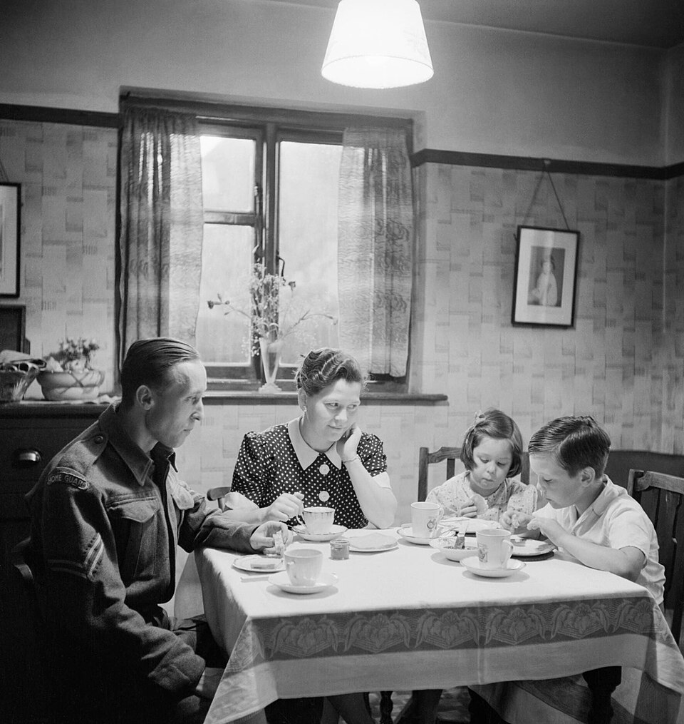 timelessbritain's tweet photo. his wife and children Elaine, 6, and David, 7, before Home Guard duty (his day still wasn’t finished).

The same photo series shows Richard at the factory helping solve a worker’s tool problem. For many working families, tea was the hearty meal waiting after the working day — not the fashionable afternoon tea of drawing rooms.

The old class line has blurred. Today the word is much more regional: “tea” remains strongest across northern England, while “dinner” dominates the South. The wartime duty faded; that family word survived.