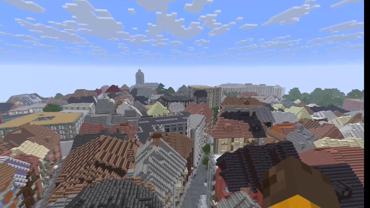 Minecraft gameplay view of a tree-lined route near Madrid’s Royal Palace, showing a walkable path, vegetation and the surrounding city context.