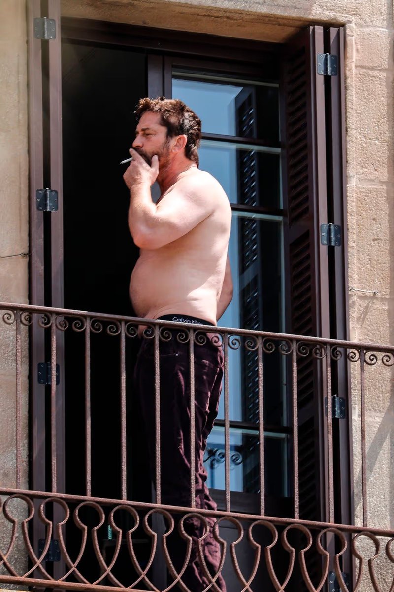 am_Migrade's tweet photo. Gerard Butler soaking up the Barcelona sunshine from his balcony, shirtless and smoking during his getaway. 😎 https://t.co/bGF7umFKZe
